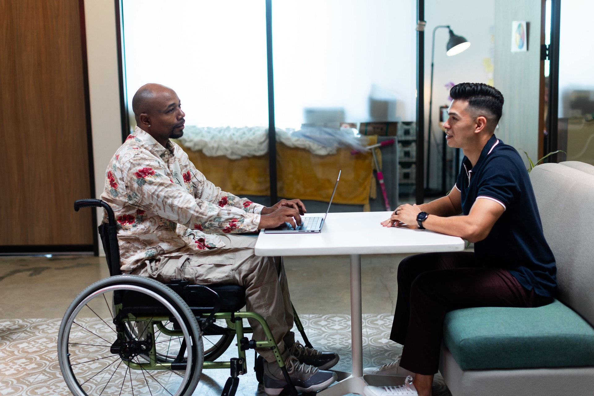 Businessman in Wheelchair Meeting with Coworker Using Laptop