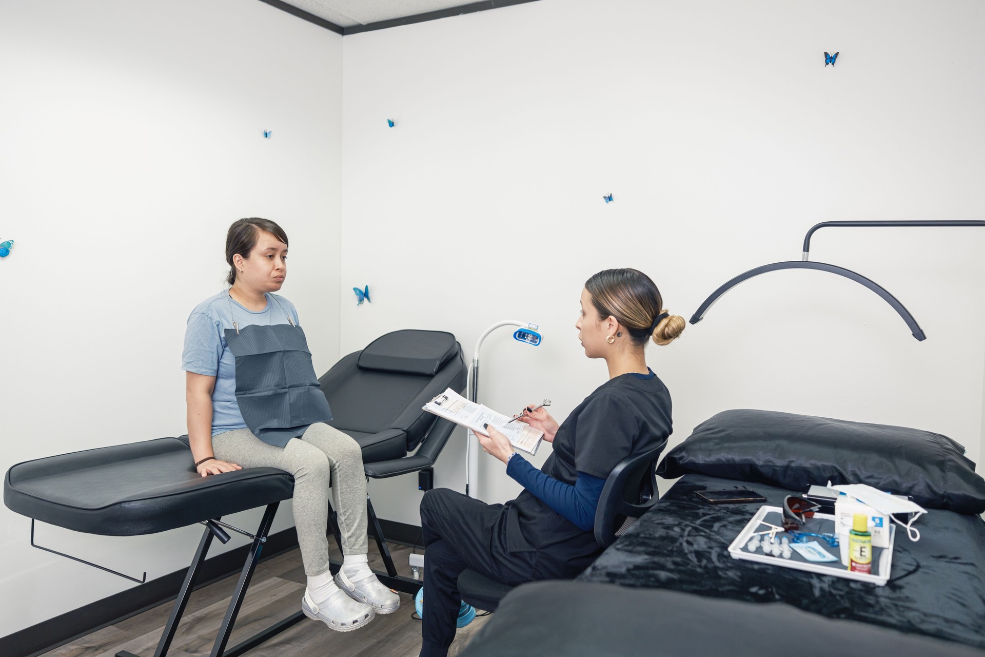 Young Mexican female technician with female client at Tooth whitening salon